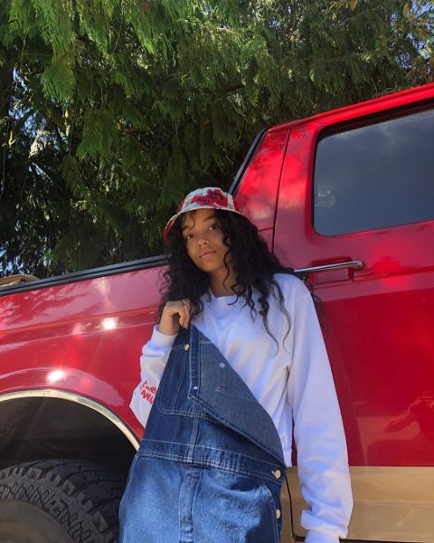 Whitney Peak in a white-blue top poses in front of a red jeep.